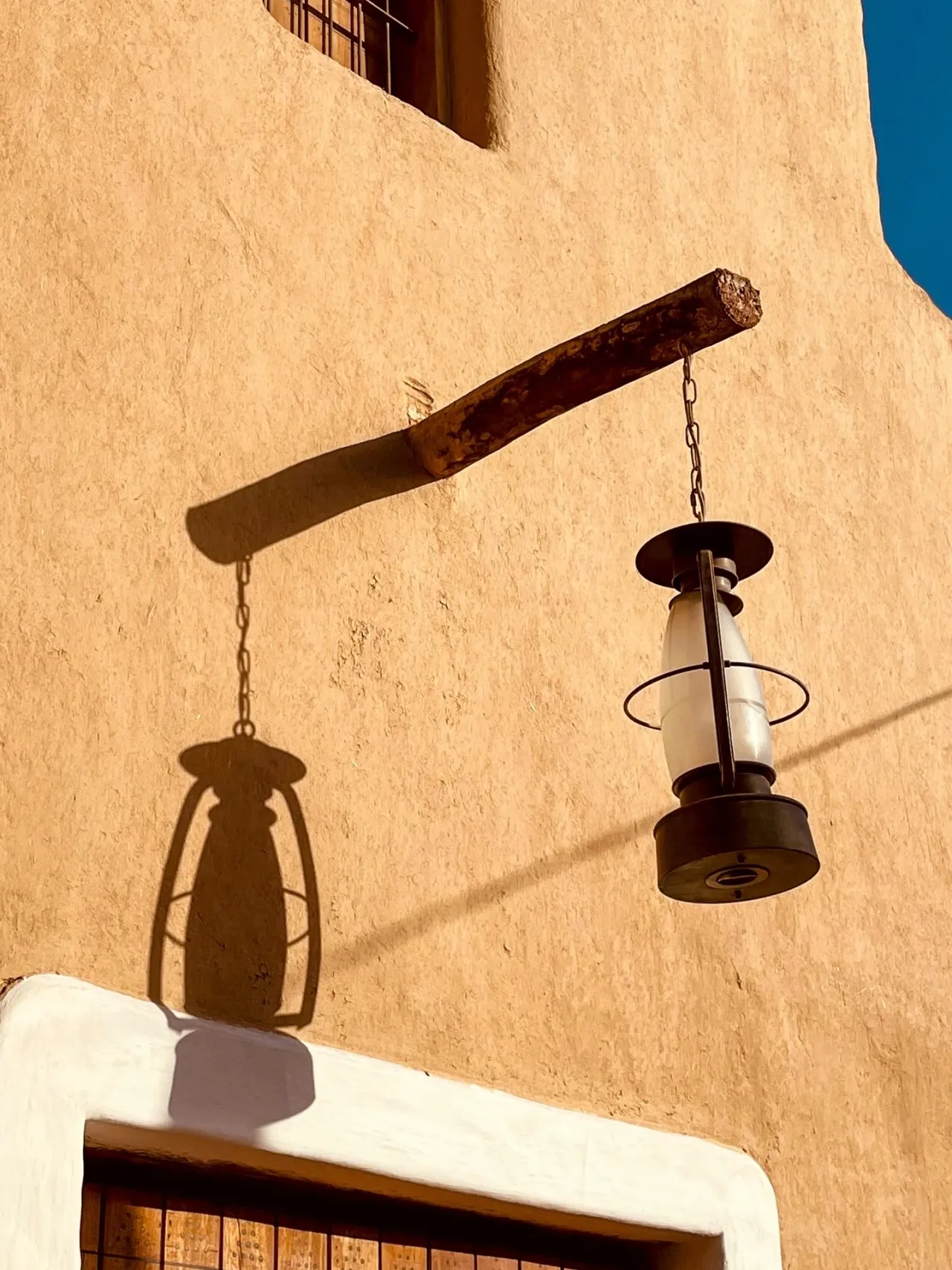 A lantern and its shadow on a warm wall