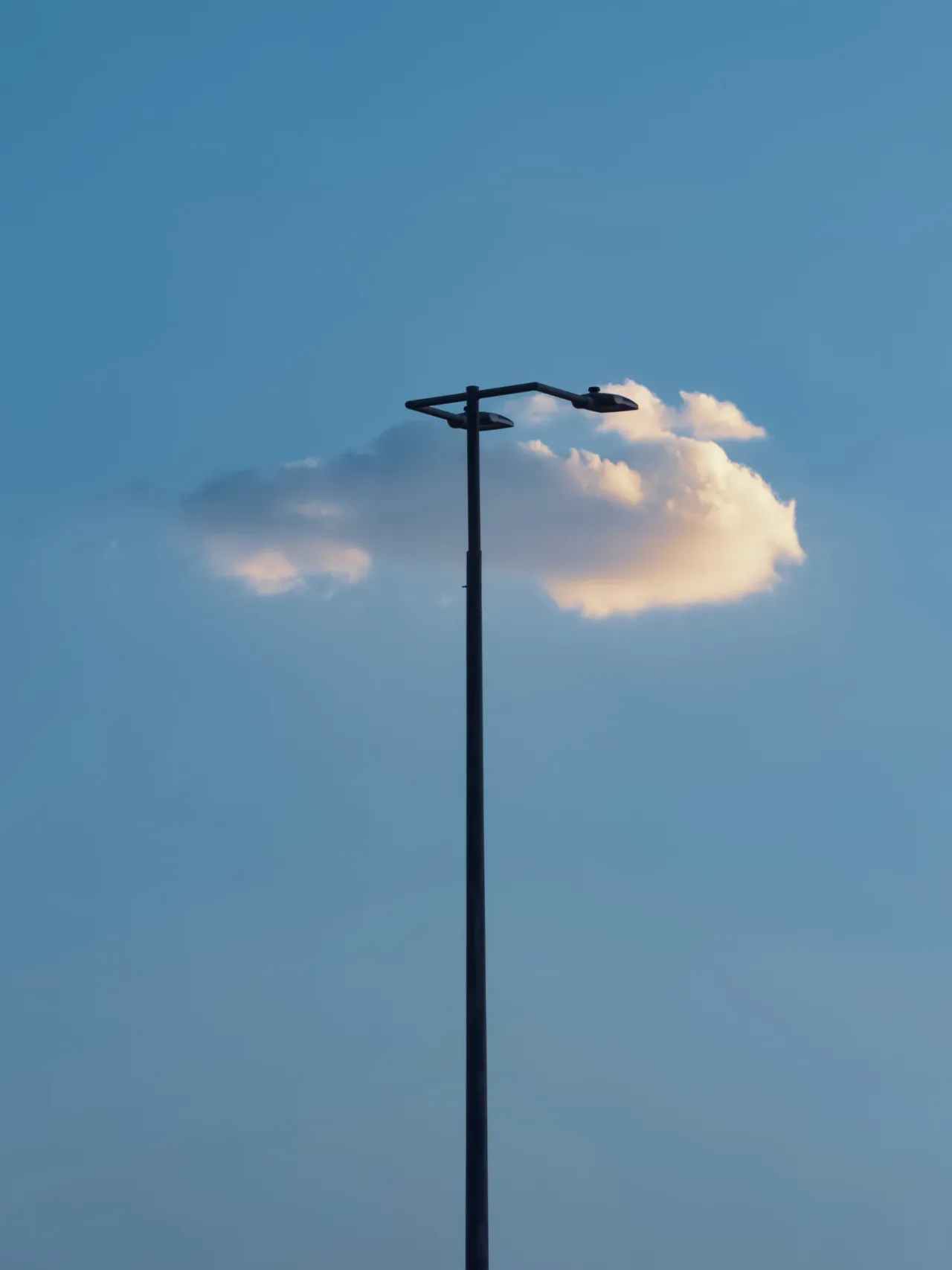 A cloud above a slender streetlight