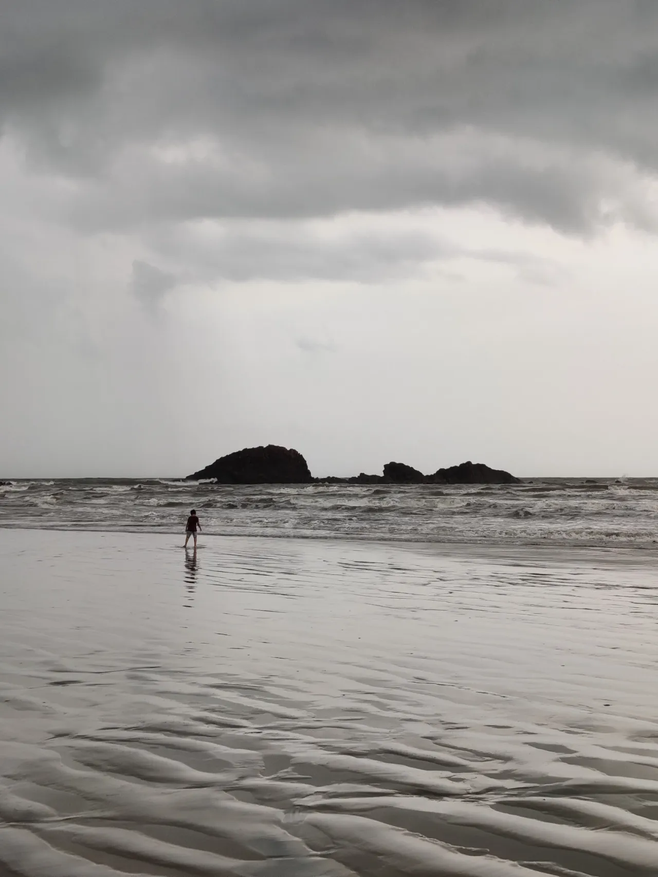 A lone figure on a beach beneath clouds